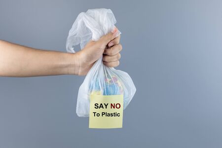 Man holding plastic bag and Globe inside against gray background with Copy space for text. Environmental Protection, Zero waste, Reusable, Say No Plastic, World Environment day and Earth day conceptの写真素材