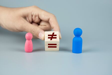 Hand change cube block of unequal to a equal sign between Pink Women and Blue Men wooden symbol. gender equality conceptの写真素材