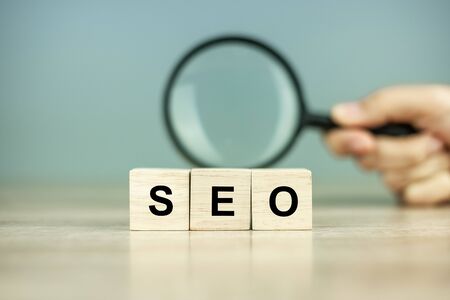 SEO (Search Engine Optimization) text wooden cubes and magnifying glass on wood table background. Idea, Vision, Strategy, Analysis, Keyword and Content conceptの写真素材