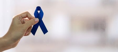 March Colorectal Cancer Awareness month, Man holding dark Blue Ribbon for supporting people living and illness. Healthcare, hope and World cancer day conceptの写真素材