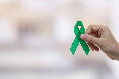 Man holding green Ribbon for supporting people living and illness. Liver, Gallbladders bile duct, kidney Cancer and Lymphoma Awareness month conceptの写真素材