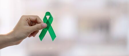 Man holding green Ribbon for supporting people living and illness. Liver, Gallbladders bile duct, kidney Cancer and Lymphoma Awareness month conceptの写真素材