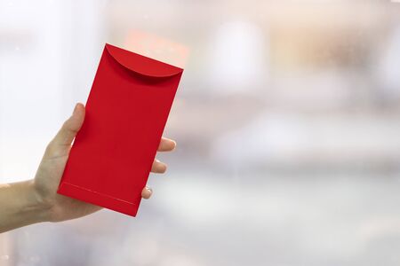 Hand holding red envelope or Ang pao. Chinese Lunar New Year celebrations conceptの写真素材