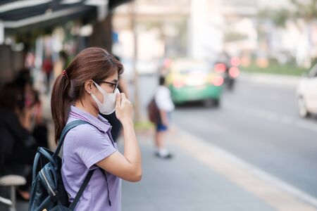 young Asian woman wearing N95 respiratory mask protect and filter pm2.5 (particulate matter) against traffic and dust city. healthcare and air pollution conceptの写真素材