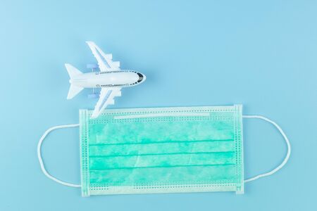 Protective face mask and airplane model on blue background.の写真素材