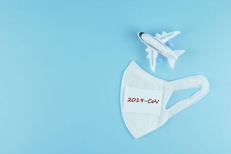 Protective face mask and airplane model on blue background.の写真素材