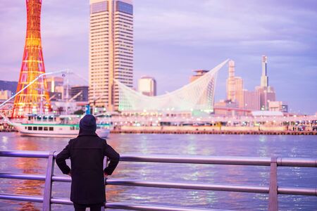 Young woman traveling at Kobe port near Osaka, Happy Asian traveler looking beautiful modern buildings at sunset. landmark and popular for tourist attractions in Kobe, Hyogo, Japan.Asia Travel conceptの写真素材