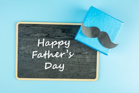 gift box with mustache on blue background, preparation for fathers. World International men day and Fathers day conceptの写真素材