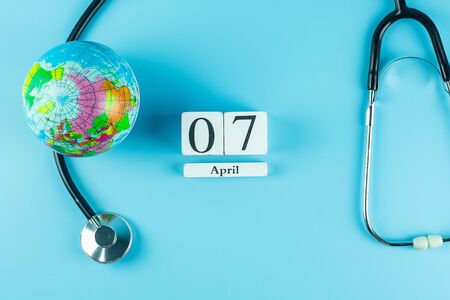 Top view Stethoscope Globe and 7th April calendar on blue background with copy space for text. Healthcare, life Insurance, world Health day conceptの写真素材
