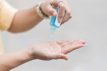 Woman hands using wash hand sanitizer gel dispenser, against Novel coronavirus or Corona Virus Disease (Covid-19) at public train station. Antiseptic, Hygiene and Healthcare conceptの写真素材