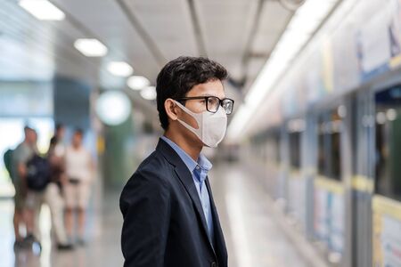 young Asian man wearing protection mask against Novel coronavirus or Coronavirus Disease (Covid-19) at public train station, is a contagious virus that causes respiratory infection.Healthcare conceptの写真素材