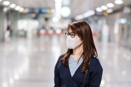 young Asian woman wearing protection mask against Novel coronavirus or Corona Virus Disease (Covid-19) at airport, is a contagious virus that causes respiratory infection.Healthcare conceptの写真素材