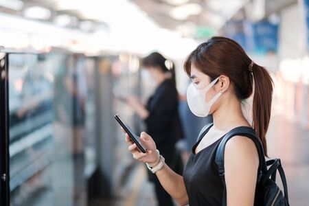 young Asian woman wearing surgical face mask against Novel coronavirus or Corona Virus Disease (Covid-19) at public train station. Hygiene, Healthcare and infection conceptの写真素材