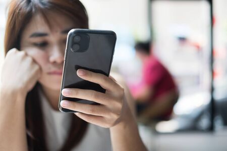 young asian Businesswoman feeling bored during using smartphone at office. Emotion, Technology and lifestyle conceptの写真素材