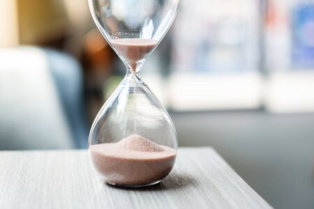 Hourglass on table office with copy space, Sand flowing through the bulb of Sandglass measuring the passing time. countdown, deadline, Life time and Retirement conceptの写真素材