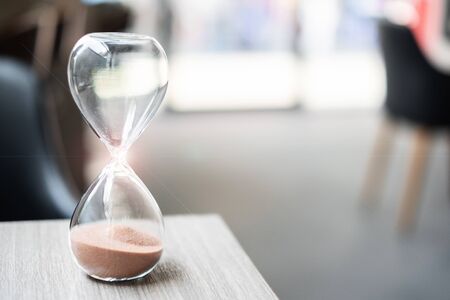Hourglass on table office with copy space, Sand flowing through the bulb of Sandglass measuring the...