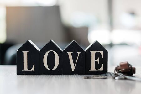 Love text with wooden Home model and key on table office. New House, Financial, Property, Happy...