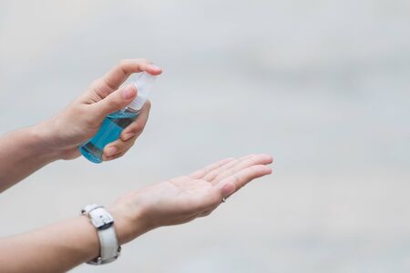 woman hand spraying hand alcohol sanitizer bottle dispenser, against Novel coronavirus or Corona Virus Disease (Covid-19) at public outdoor. Antiseptic, Hygiene and Healthcare conceptの写真素材