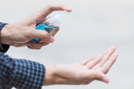 man hand spraying hand alcohol sanitizer bottle dispenser, against Novel coronavirus or Corona Virus Disease (Covid-19) at public outdoor. Antiseptic, Hygiene and Healthcare conceptの写真素材