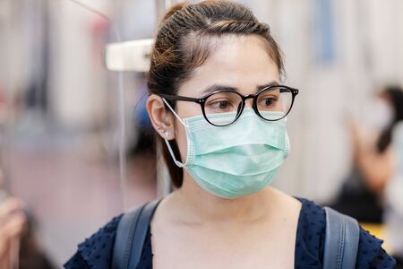 young Asian woman wearing Surgical face mask against Novel coronavirus or Corona Virus Disease (Covid-19) at public subway train. Hygiene, Healthcare and infection conceptの写真素材