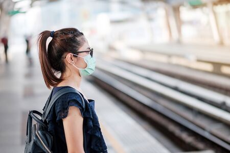 young Asian woman wearing Surgical face mask against Novel coronavirus or Corona Virus Disease (Covid-19) at public train station. Hygiene, Healthcare and infection conceptの写真素材