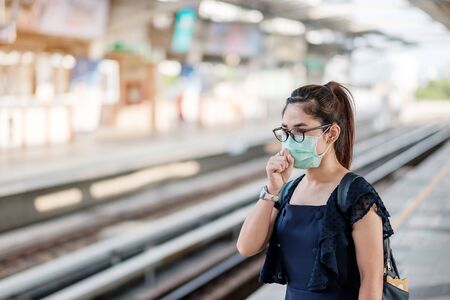 young Asian woman wearing Surgical face mask against Novel coronavirus or Corona Virus Disease (Covid-19) at public train station. Hygiene, Healthcare and infection conceptの写真素材