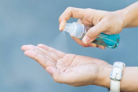 woman hand spraying alcohol sanitizer bottle dispenser, against Novel coronavirus or Corona Virus Disease (Covid-19) at public outdoor. Antiseptic, Hygiene and Healthcare conceptの写真素材