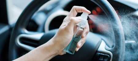 man hand spraying alcohol sanitizer on steering wheel in his car, against Novel coronavirus or Corona Virus Disease (Covid-19). Antiseptic, Hygiene and Healthcare conceptの写真素材