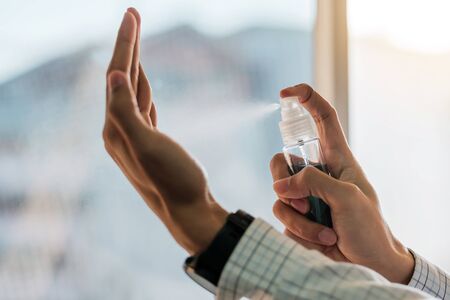 Man hand spraying alcohol sanitizer bottle dispenser, against Novel coronavirus or Corona Virus Disease (Covid-19) at public outdoor. Antiseptic, Hygiene and Healthcare conceptの写真素材