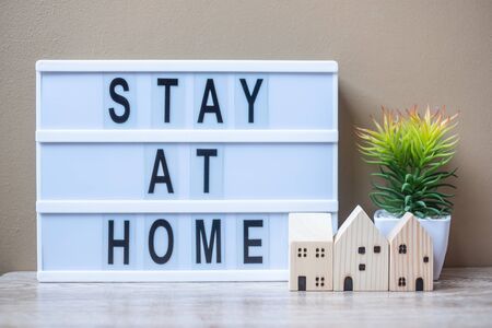 wooden Home model and lightbox with text STAY AT HOME on table. Coronavirus, Covid-19, Quarantines and Social Distancing conceptの写真素材