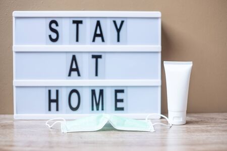 lightbox with text STAY AT HOME, hand alcohol gel or sanitizer and Surgical mask on table. Coronavirus, Covid-19, Quarantines and Social Distancing conceptの写真素材