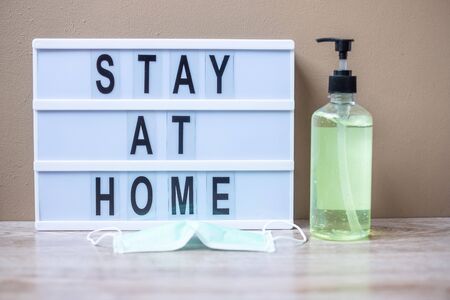 lightbox with text STAY AT HOME, hand alcohol gel or sanitizer and Surgical mask on table. Coronavirus, Covid-19, Quarantines and Social Distancing conceptの写真素材