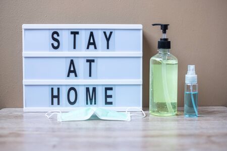 lightbox with text STAY AT HOME, hand alcohol gel or sanitizer and Surgical mask on table. Coronavirus, Covid-19, Quarantines and Social Distancing conceptの写真素材