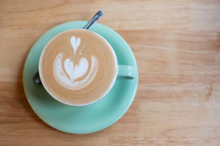 Cup of hot art cappuccino coffee on wooden table in cafe shopの写真素材