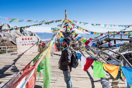 Young woman traveler traveling at Shika Snow Mountain or Blue Moon Valley in Zhongdian city (Shangri-La). Yunnan, China. Chinese character means 4500 meters above sea levelの写真素材