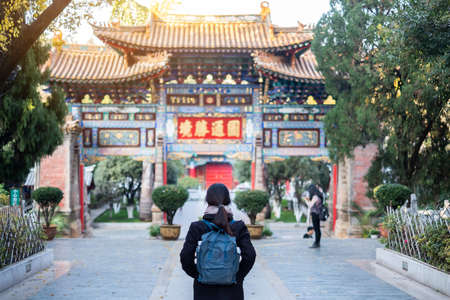 happy woman traveler with sweater and backpack traveling in Yuantong Temple, Buddhist temple in Kunming. landmark and popular for tourists attractions in Kunming, Yunnan, China. Asia travel conceptのeditorial素材