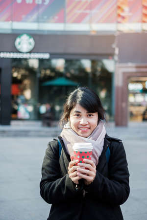 Woman hands holding hot Starbucks coffee paper cup, for Christmas and Happy New Year collection. Kunming, China, December 10, 2019のeditorial素材