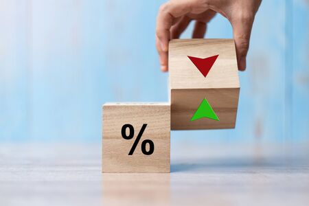 business man Hand change wood cube block with percentage to UP and Down arrow symbol icon. Interest rate, stocks, financial, ranking, mortgage rates and Cut loss conceptの写真素材