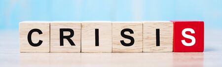 wooden cube blocks with CRISIS text on table background. Coronavirus pandemic, risk, fall Business,...