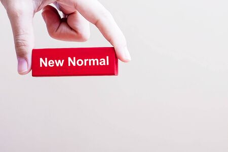 Man hand holding NEW NORMAL red blocks, the end of Coronavirus pandemic. Human lifestyle Behavior...