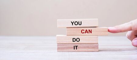 YOU CAN DO IT wooden blocks on table background, Businessman hand placing or pulling wooden block with CAN word on the tower. Business and Attitude Positive Conceptsの写真素材