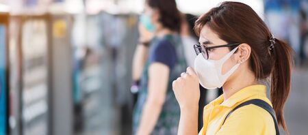 young Asian woman wearing protection face mask prevent coronavirus or Corona Virus Disease (Covid-19) at public train station. Infection and Pandemic conceptの写真素材