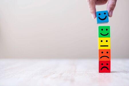 Emotion face symbol on yellow wooden cube blocks. Service rating, ranking, customer review, satisfaction and feedback concept.の写真素材