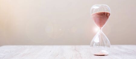 Hourglass on table, Sand flowing through the bulb of Sandglass measuring the passing time. countdown, deadline, Life time and Retirement conceptの写真素材