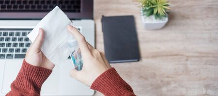 Woman cleaning laptop by wet wipes tissue and alcohol disinfectant on workplace during working and online learning at home office, protection coronavirus (Covid-19) infection. New Normal conceptの写真素材