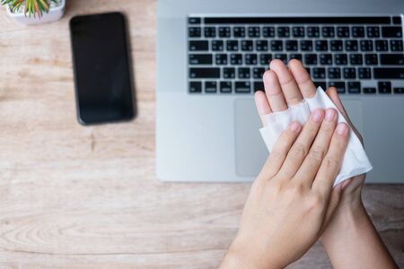 Woman cleaning hands and devices by wet wipes tissue and alcohol disinfectant on workplace during work at home office, protection coronavirus (Covid-19) infection. New Normal and Clean surface conceptの写真素材