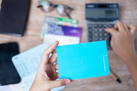 Woman holding savings deposit passbook and using calculator at home office tax and retirement planning conceptsの写真素材