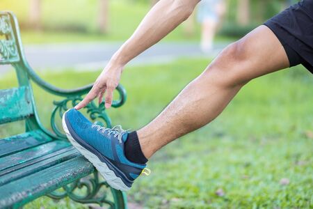 Young adult male in red sportswear stretching muscle in the park outdoor, runner man warm up ready for running and jogging in morning. wellness, fitness, exercise and healthy lifestyle conceptsの写真素材