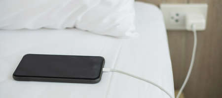mobile smart phone charging battery on bed in the bedroom at home. Technology, multiple sharing and...