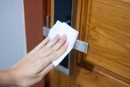 Woman hand cleaning digital door handle by wet wipe tissue, protection coronavirus or Corona Virus Disease (Covid-19) at home. Clean surface, Antiseptic, lifestyle, Hygiene and New normal conceptの写真素材